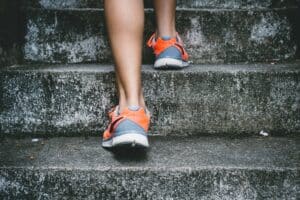 view of man's feet ascending concrete steps in running shoes